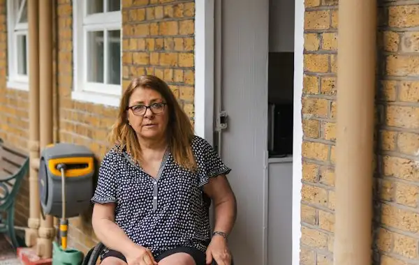 A woman in a wheelchair at the doorway of her home