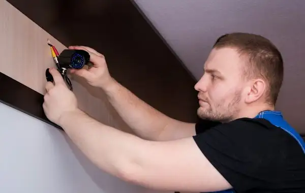 A technician securing a fixture on a wall