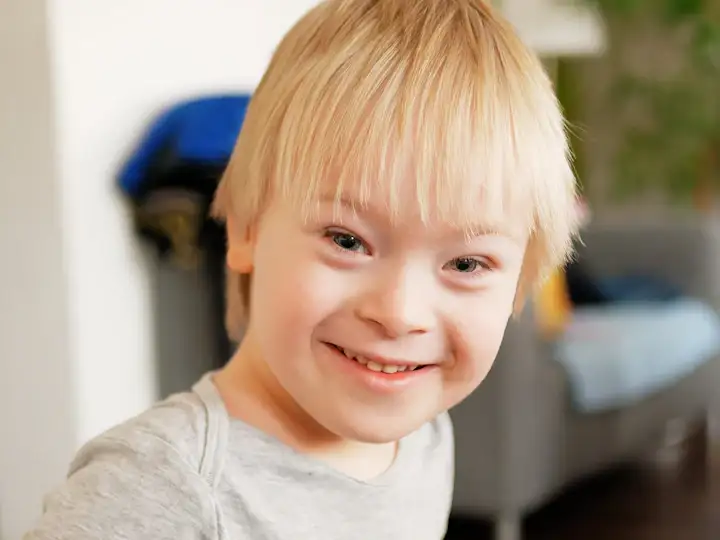 A smiling boy with Down syndrome at home