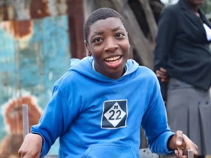 A smiling young Black man sitting in a wheelchair